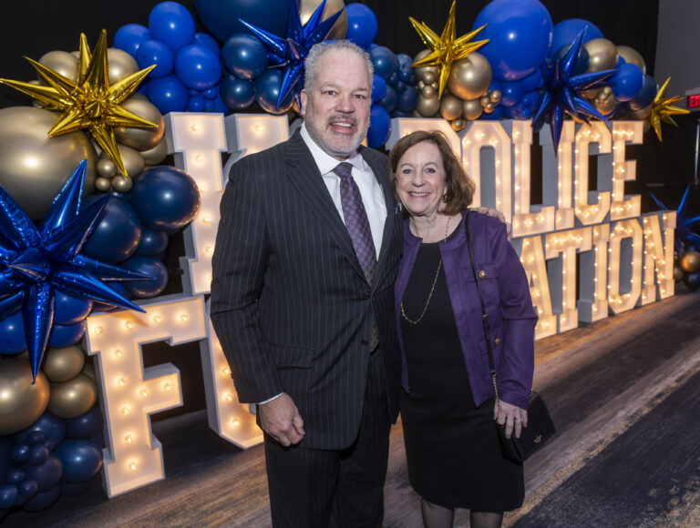 Couple posing in front of lighted Police Foundation marquee letters at A Call for BackUp